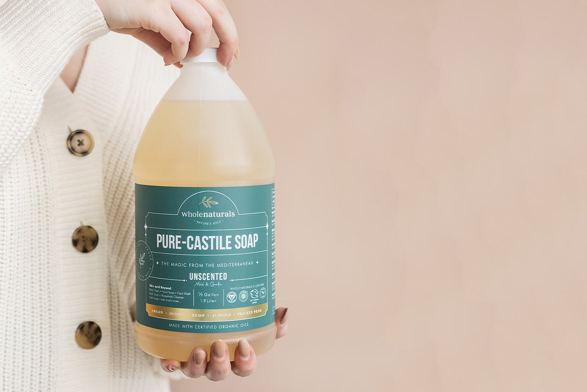 Hands holding a half gallon bottle of Pure-Castile Soap, the concentrate diluted at equal parts for body wash and hand soap