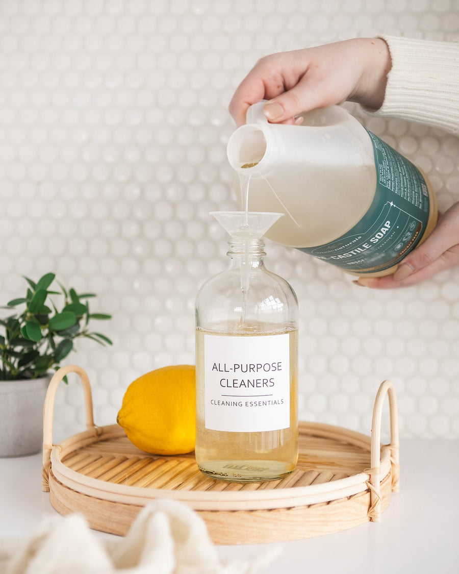 Pouring Pure-Castile Soap through a funnel into a labeled all-purpose cleaner bottle