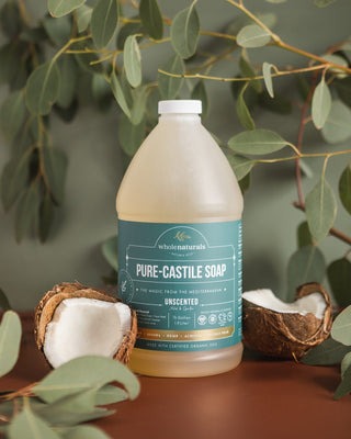 Bottle of Pure-Castile Soap with fresh coconut halves and eucalyptus leaves