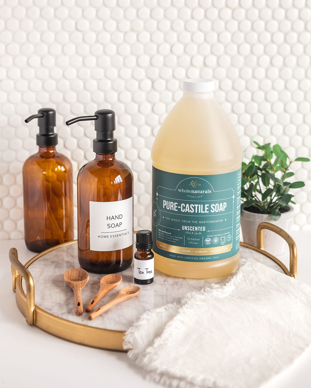 Amber pump dispensers labeled hand soap on a tray next to a bottle of Pure-Castile Soap