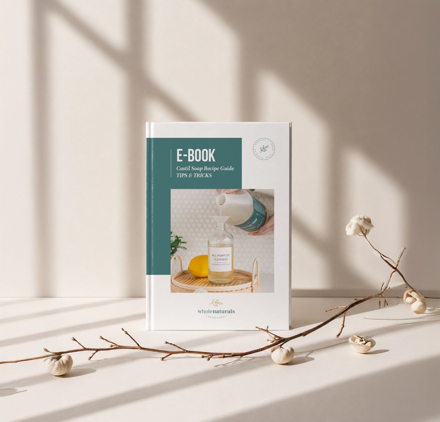 The Whole Naturals castile soap recipe guide, standing on a sunlit ledge beside a dried branch